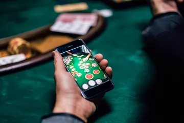Un homme concentré sur son ordinateur portable avec des statistiques en direct en arrière-plan, mettant en avant les fonctions sport et casino de l'application mobile KWANZA.