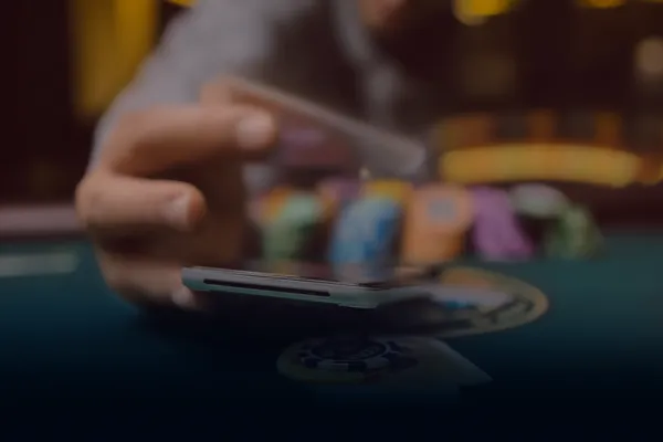 Une femme sourit en jouant en ligne sur son ordinateur portable au milieu d'éléments de casino lumineux, illustrant la collection variée de jeux proposée par KWANZA.