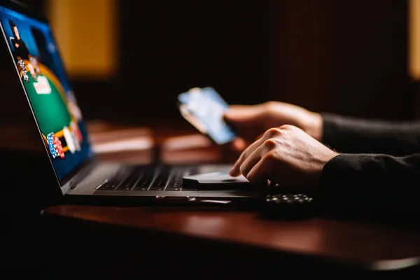 Une femme en robe verte luxueuse se tient près d'une roulette ornée, capturant l'ambiance haut de gamme du casino KWANZA.